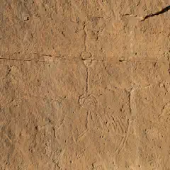 A sandstone wall incorporates petroglyphs including linear designs and a humanlike form.