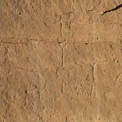 A sandstone wall incorporates petroglyphs including linear designs and a humanlike form.