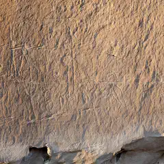 A large rock face features several petroglyphs carved into its surface.