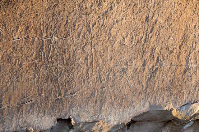 A large rock face features several petroglyphs carved into its surface.