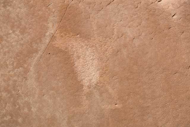 A rock surface with a faded, indistinct figure etched into it.