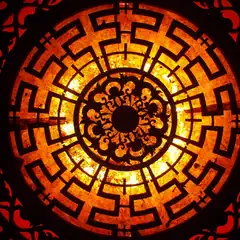 A circular design features a central black floral element surrounded by a labyrinthine pattern in shades of orange and yellow.