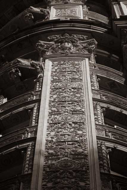 A tall, intricately carved stone panel rises within a curved, ornate architectural space, flanked by detailed columns and decorative moldings.