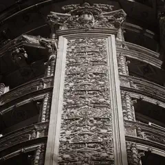 A tall, intricately carved stone panel rises within a curved, ornate architectural space, flanked by detailed columns and decorative moldings.