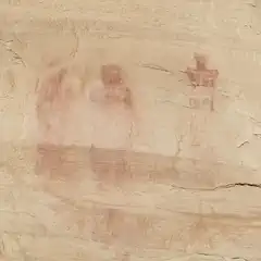 Three human figures painted in red on a rocky surface.