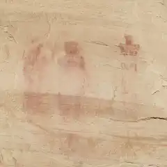 Three human figures painted in red on a rocky surface.