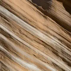 A rock face displays diagonal bands of brown and white sediment.
