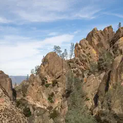 A rugged, eroded rock formation rises sharply with sparse vegetation clinging to its slopes.