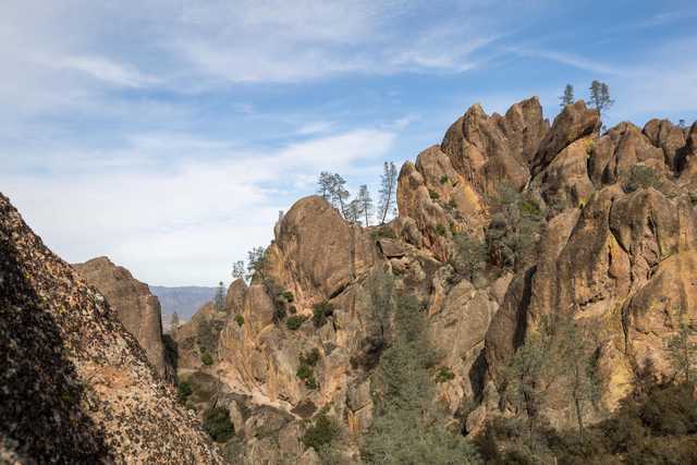 A rugged, eroded rock formation rises sharply with sparse vegetation clinging to its slopes.