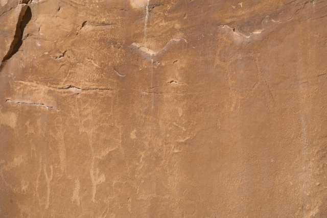 A rock face with faint, carved human figures.