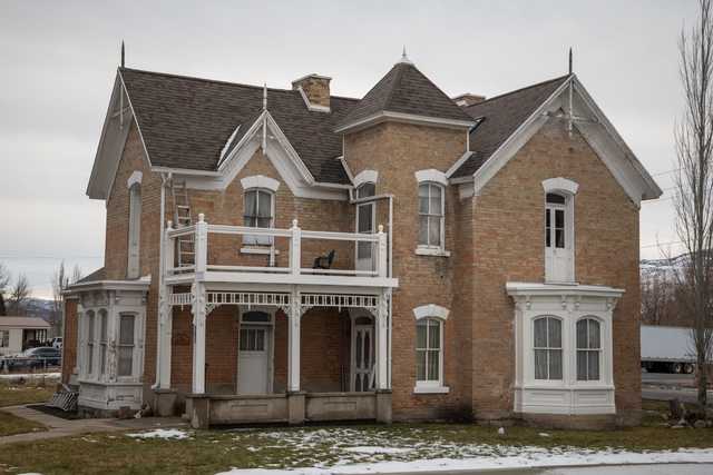 A two-story brick house with white trim and a dark brown roof. It is set amidst partially snowy lawns.