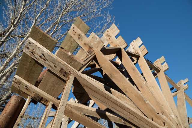 A wooden water wheel seen from below.