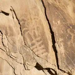 A rock face features a petroglyph of two human-like figures.