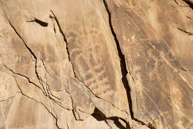 A rock face features a petroglyph of two human-like figures.