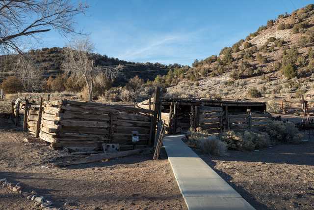 A concrete pathway leads to a dilapidated wooden structure in a desert landscape.