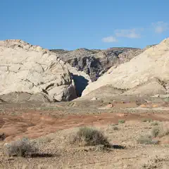 A canyon cuts through tan rock formations under a clear blue sky.