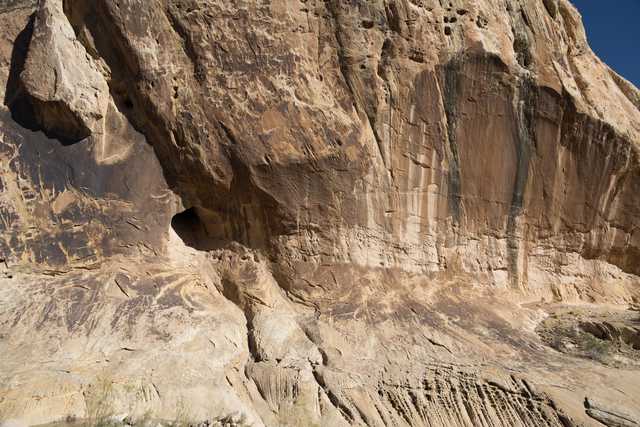 A rugged cliff face with layered rock formations and a small cave-like opening.