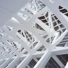 A complex network of white structural beams and geometric patterns forms an intricate architectural design.
