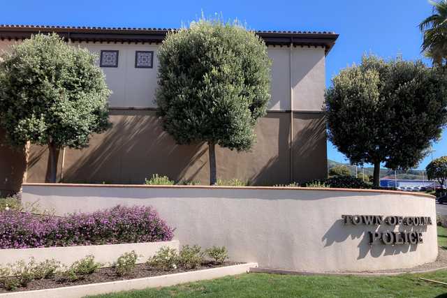 A sign reads Town of Colma Police in front of a beige building.