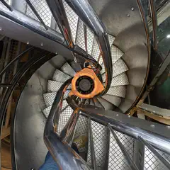 A spiral staircase descends into a cylindrical structure.