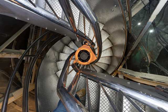 A spiral staircase descends into a cylindrical structure.