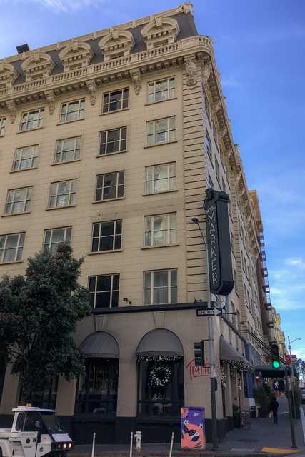 The Hotel Marker, a multi-story building with ornate architectural details, stands at a street corner under a clear blue sky.
