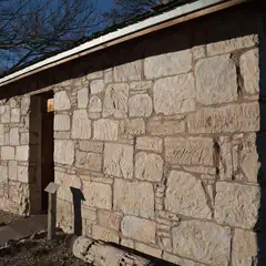 A stone building with a wooden door and a sloped roof.
