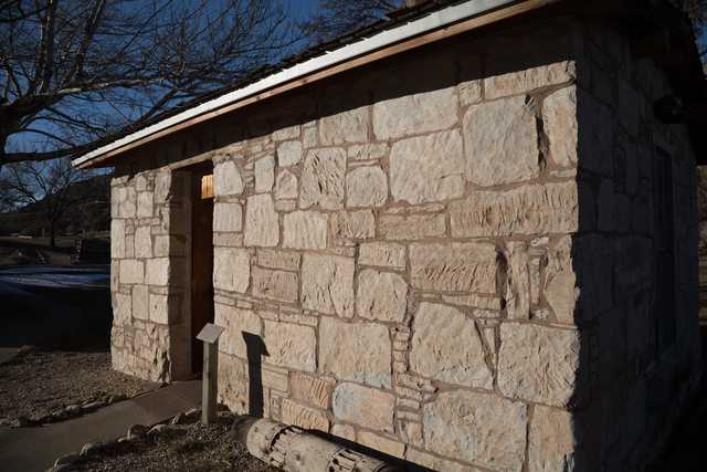 A stone building with a wooden door and a sloped roof.