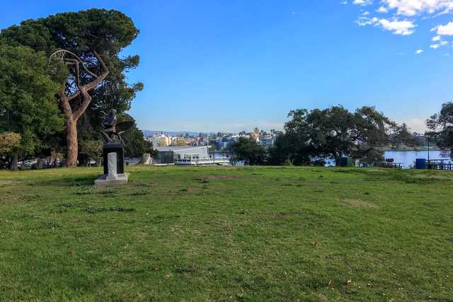 A statue is placed in the middle of a park near a lake.
