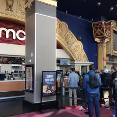 A group of people standing in line at a concession counter inside a movie theater.