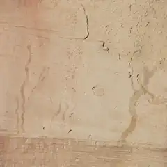 A section of a rock wall features faint markings that resemble wavy lines, as well as small circles and other indistinct shapes.